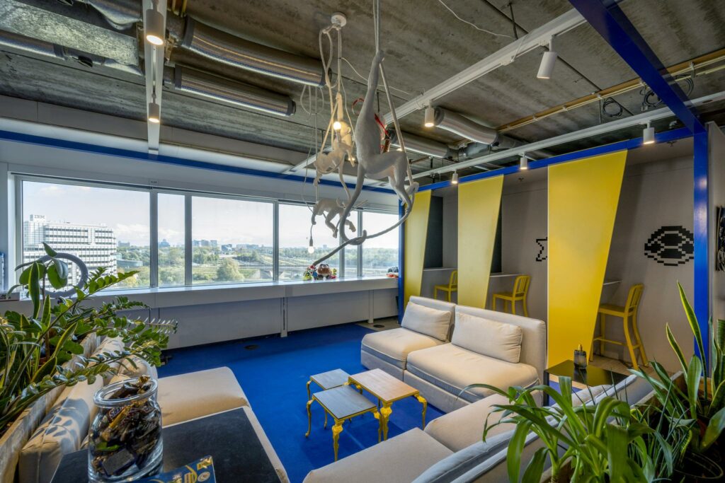 Modern ingericht kantoor aan de Johan Huizingalaan met kleurrijke zitplekken, speelse decoratie en uitzicht op het IBM-gebouw.